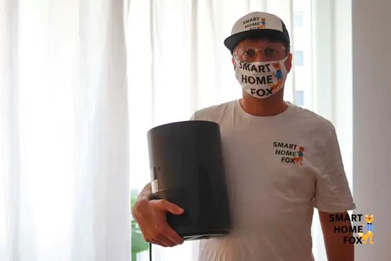 A person has an air purifier in his hand and wears a respirator mask